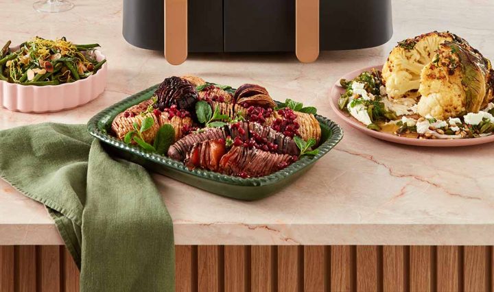 A selection of side dishes including, from left to right, air-fried green beans, air-fried hasselback root vegetables and a whole air-fried cauliflower.