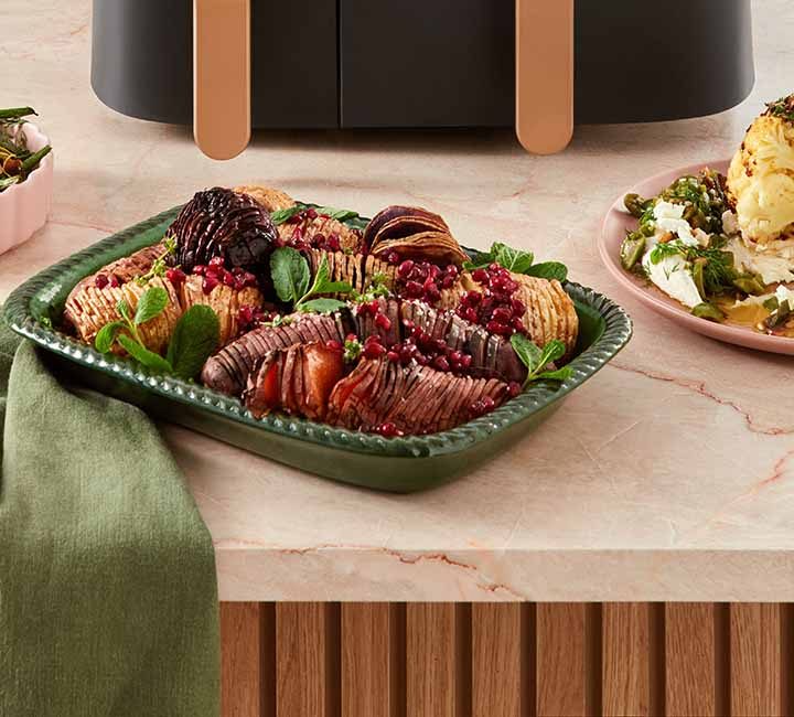 A selection of side dishes including, from left to right, air-fried green beans, air-fried hasselback root vegetables and a whole air-fried cauliflower.