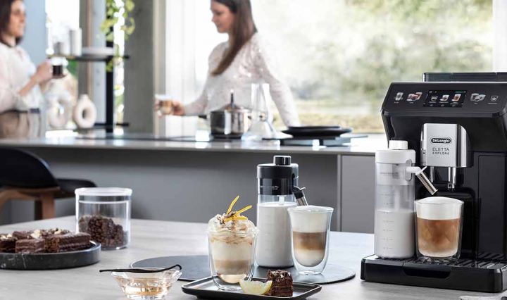 DeLonghi Eletta Explore on bench with drinks and dessert.