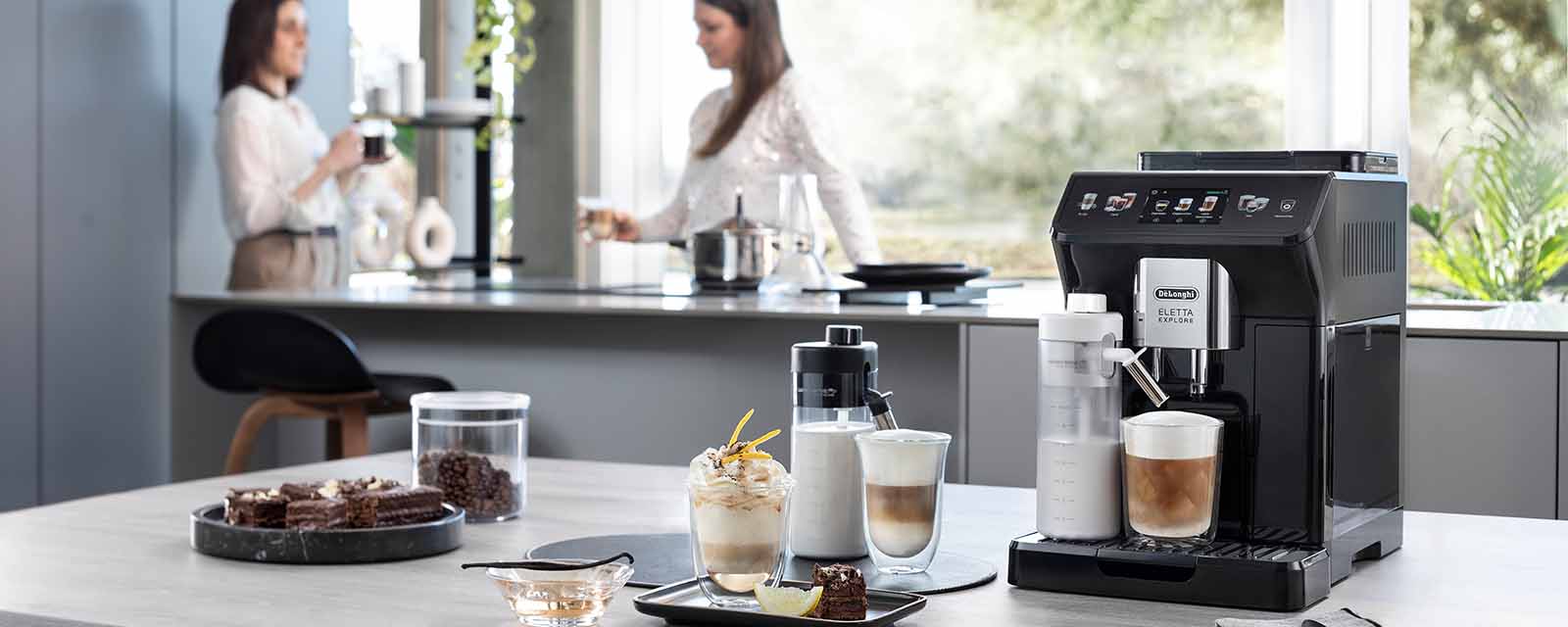 DeLonghi Eletta Explore on bench with drinks and dessert.