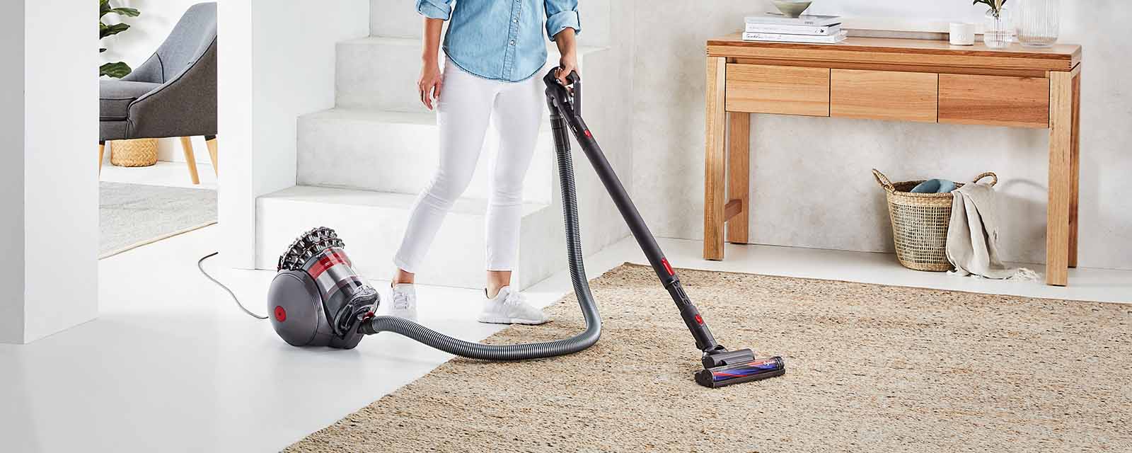 A person cleaning a rug with the Dyson Cinetic Big Ball Vacuum.