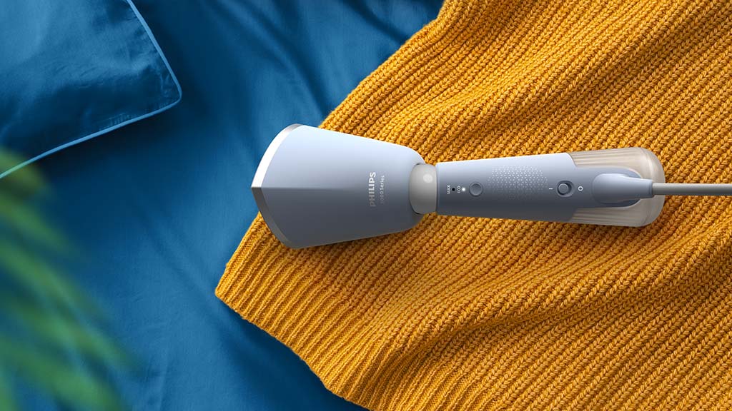 Image of the Philips 5000 Series Handheld Garment Steamer laying on a knitted jumper.