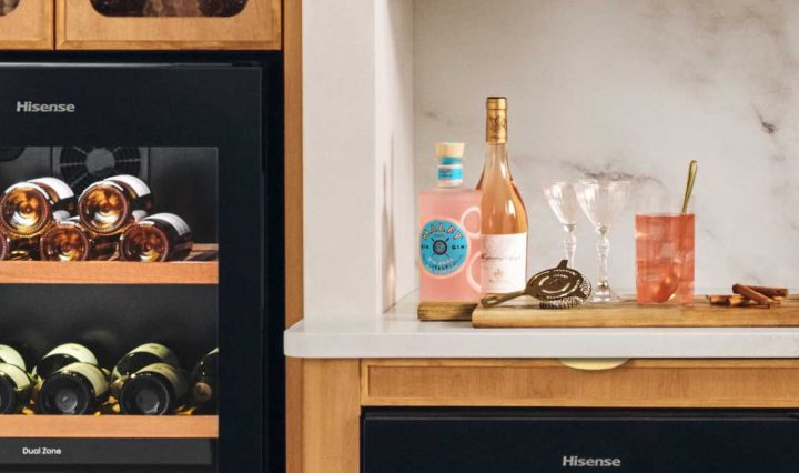 A drinks tray sits on a kitchen countertop with ingredients visible to make the Pink Gin 75 cocktail, including a bottle of Pink Gin.