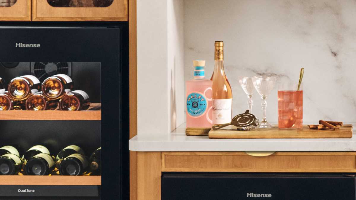 A drinks tray sits on a kitchen countertop with ingredients visible to make the Pink Gin 75 cocktail, including a bottle of Pink Gin.