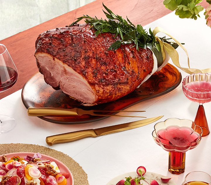 A Christmas dinner or lunch spread with a large glazed ham and a selection of sides.