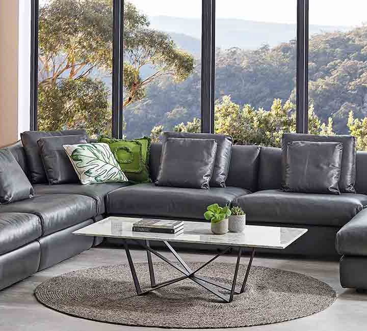 A Leather Lounge in front of a window with a bush view.
