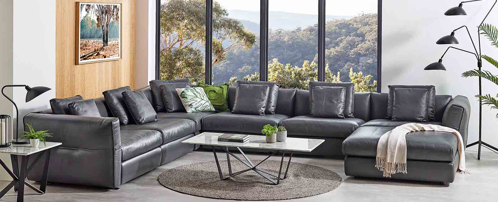 A Leather Lounge in front of a window with a bush view.