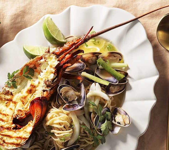 Lobster E-fu Noodle with Pippies and Cuttlefish on a tablecloth.