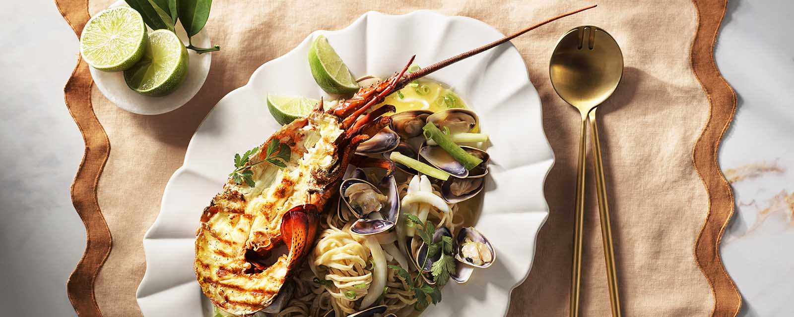 Lobster E-fu Noodle with Pippies and Cuttlefish on a tablecloth.