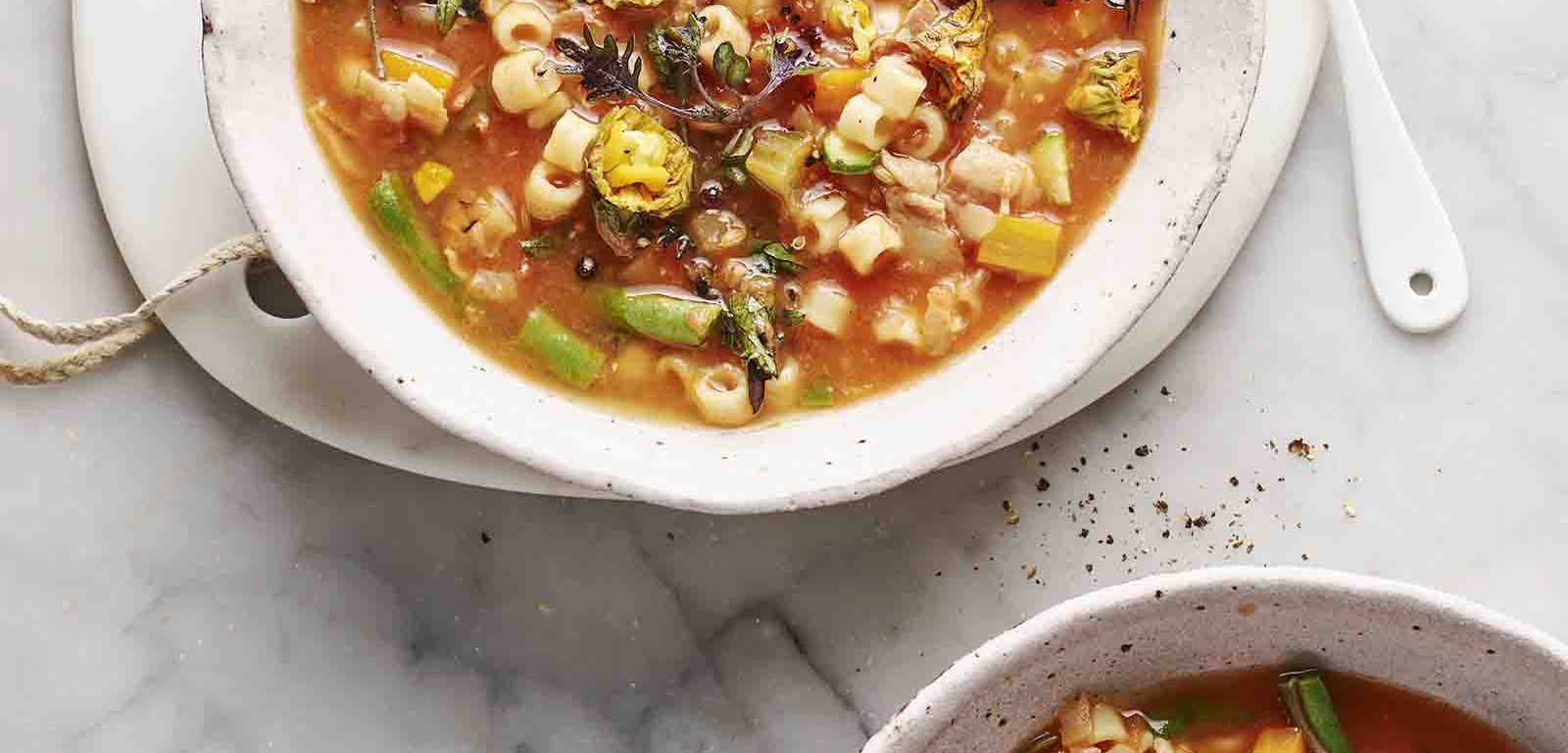 Two bowls of Minestrone with Pancetta, Zucchini Flowers and Baby Kale.