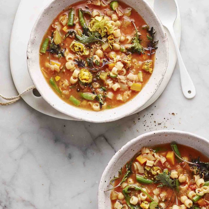 Two bowls of Minestrone with Pancetta, Zucchini Flowers and Baby Kale.