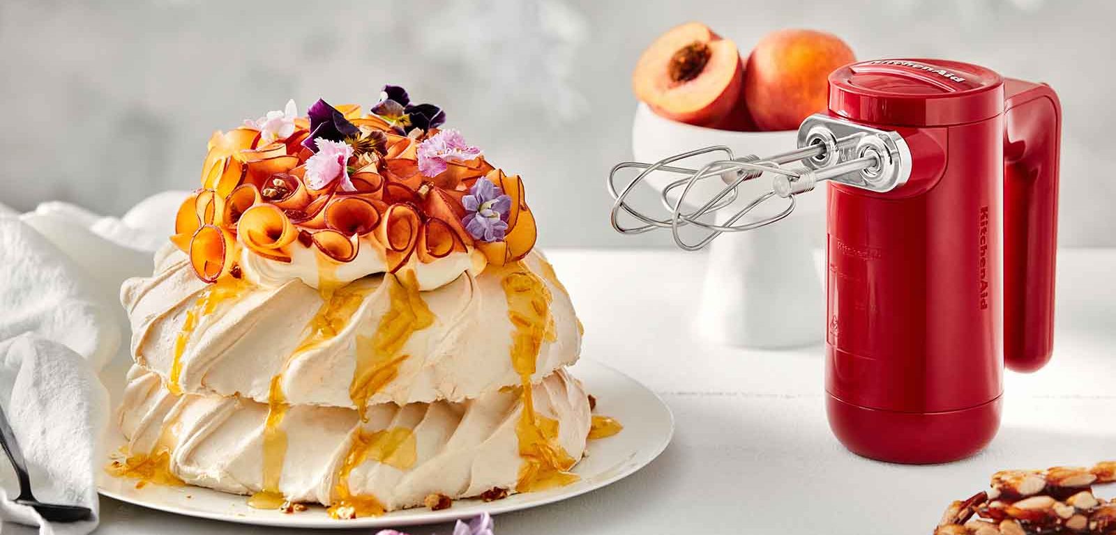 Pavlova Stack with Peaches and Almond Praline next to the KitchenAid Cordless Hand Mixer.