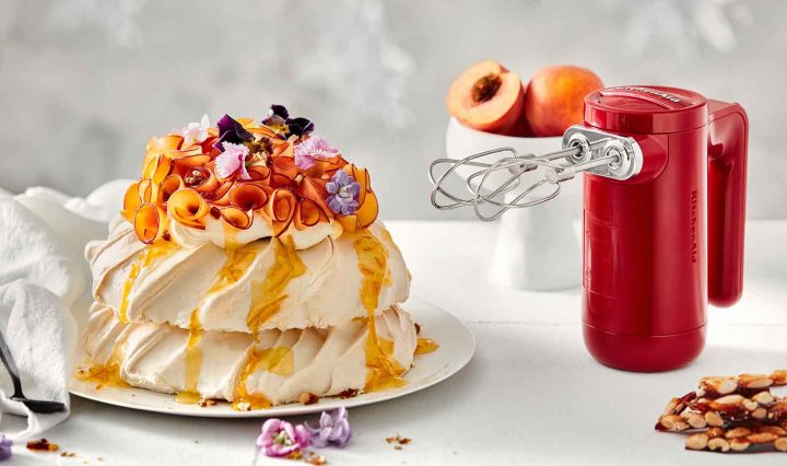 Pavlova Stack with Peaches and Almond Praline next to the KitchenAid Cordless Hand Mixer.