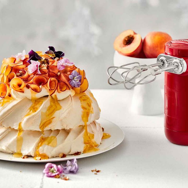 Pavlova Stack with Peaches and Almond Praline next to the KitchenAid Cordless Hand Mixer.