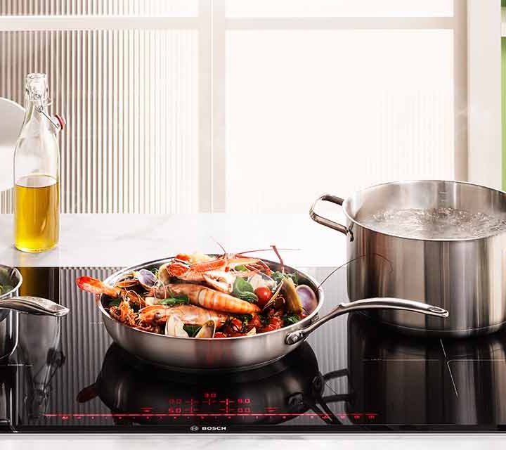 Braised seafood, fennel & saffron with aioli & warrigal greens cooking on the Bosch 900mm Series 8 5 Zone Induction Cooktop.