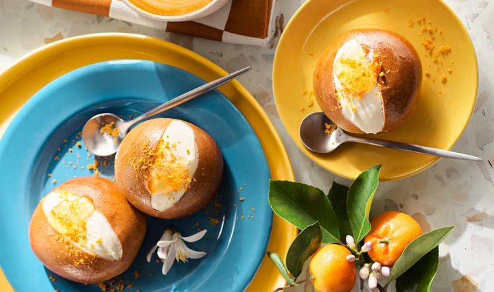 Garnished Maritozzi on blue and yellow plates.