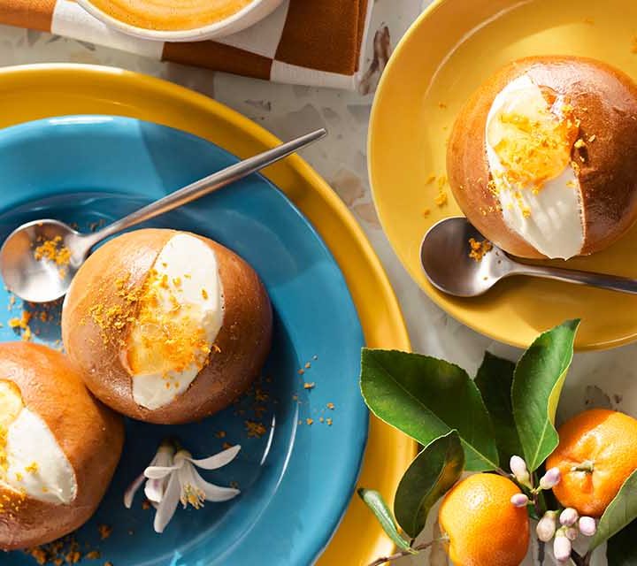 Garnished Maritozzi on blue and yellow plates.