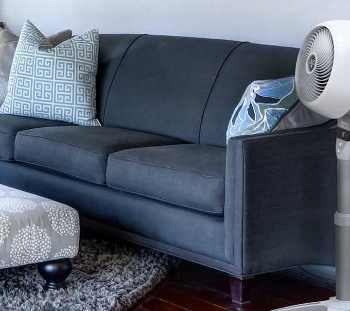 The Vornado’s Energy Smart™ Pedestal Air Circulator next to a couch.