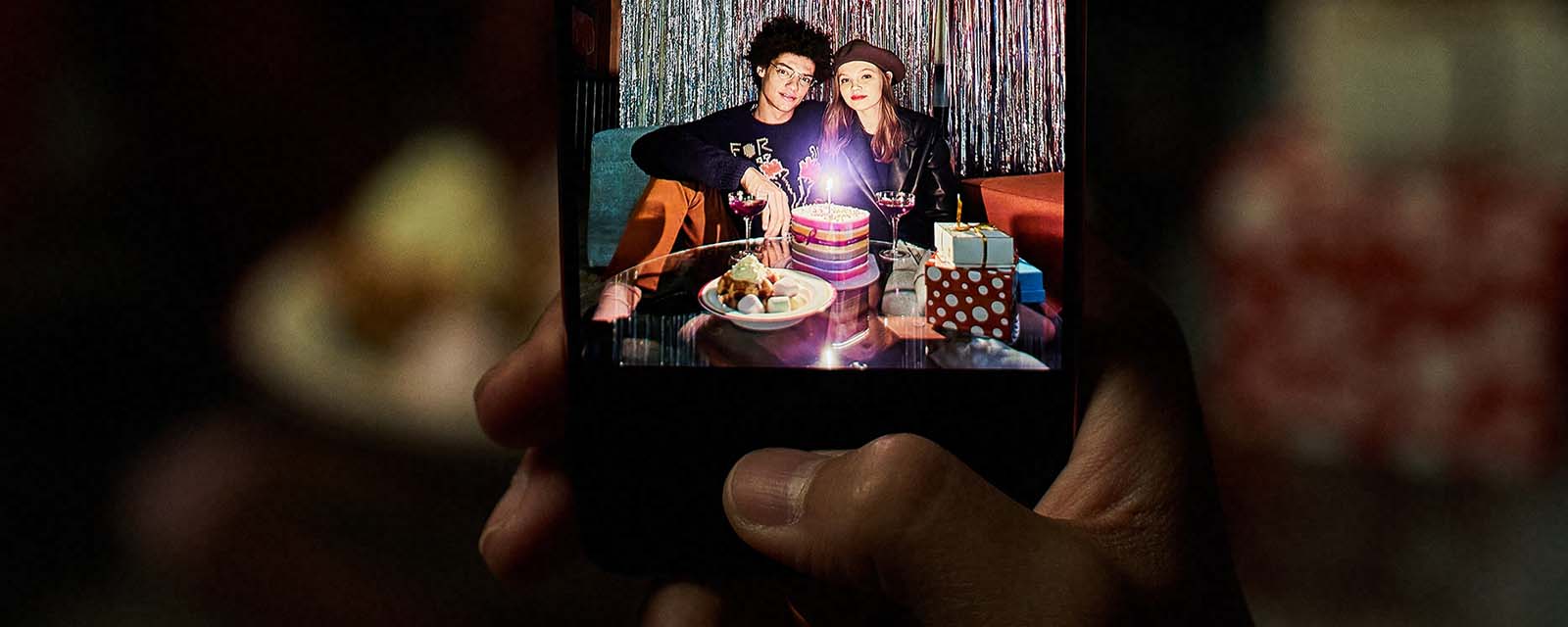 A person using a Samsung Galaxy to take a photo of people on their birthday.