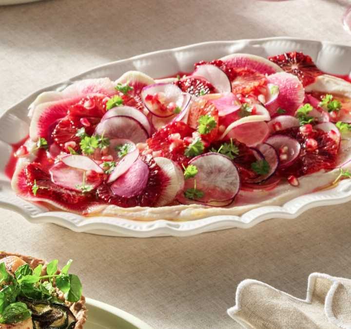 A white serving platter set on a cream table, showing the finished salad recipe ready to serve.