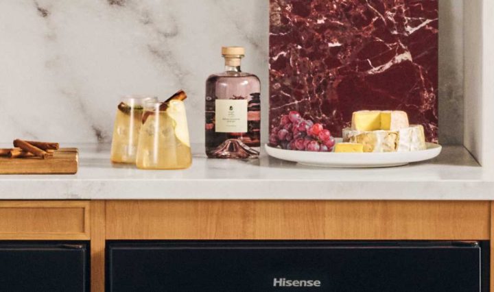 White kitchen countertop showing two Spiced Pear Mules in stemless glasses. A serving platter and bottle of liquer is to the right, with a soft cheese and berries on the serving platter as a suggestion.
